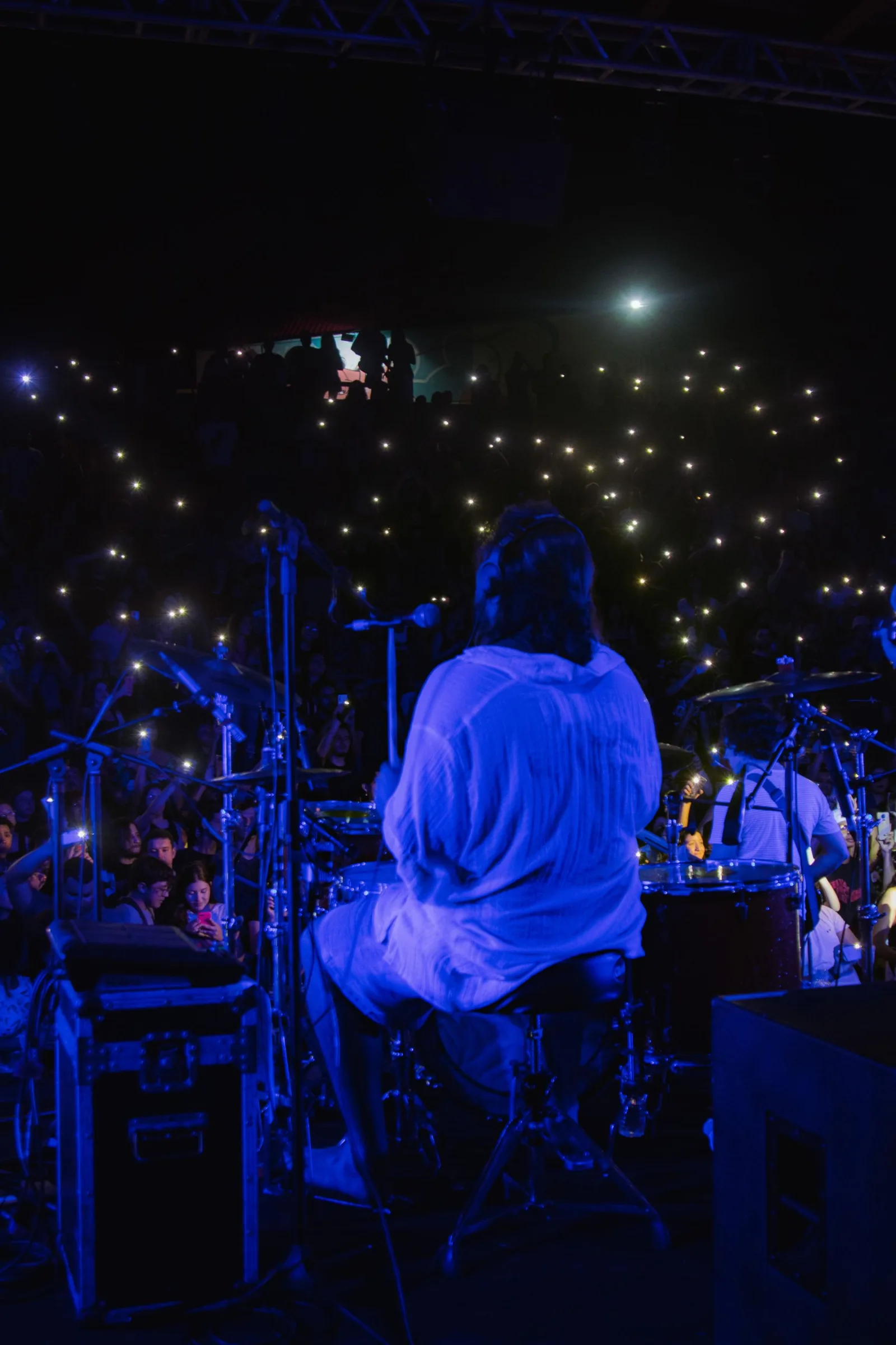 The drums from behind, phone lights in the dark beyond.