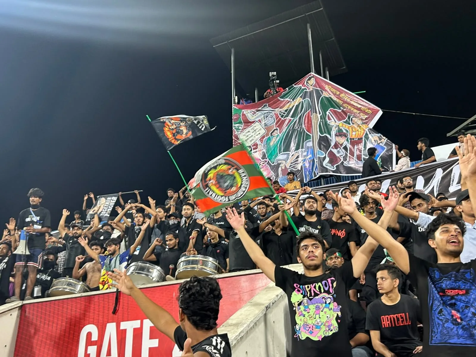 The block at night with drums, flags and a painted tifo above.