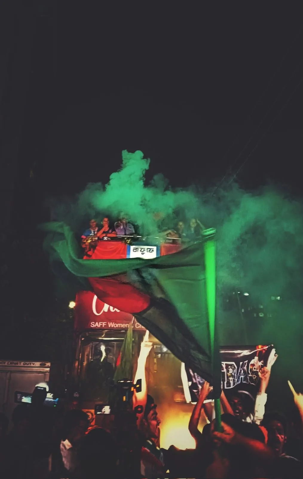 The flag and green smoke round the women's team bus at night.