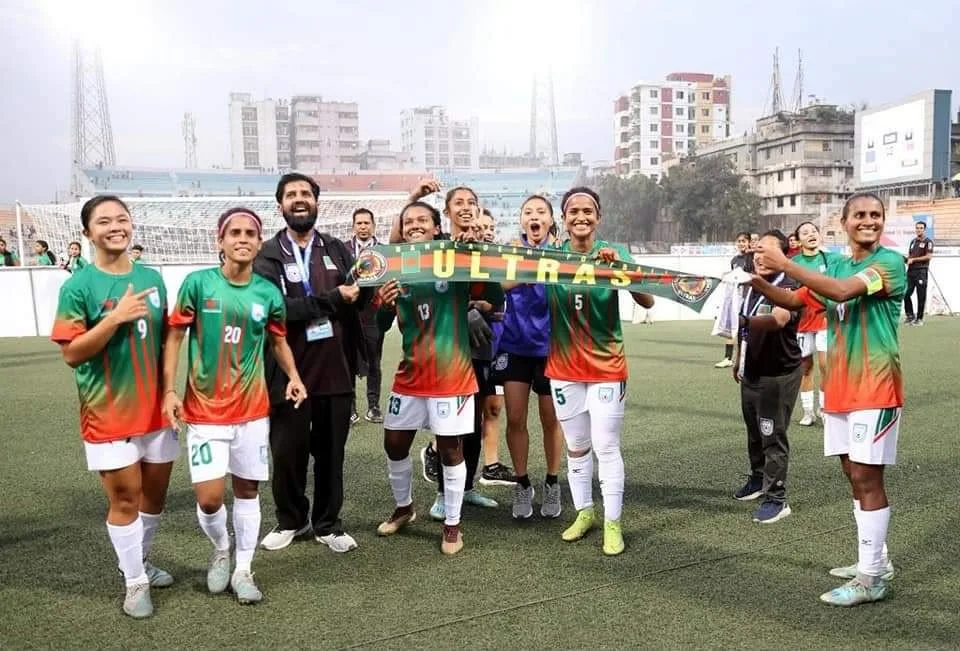 The women's team holding up the Ultras scarf on the pitch.